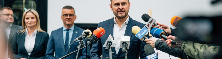 Wypowiedź Michała Rado - w tle Zarząd Spółki Koleje Dolnośląskie na tle pociągu KD